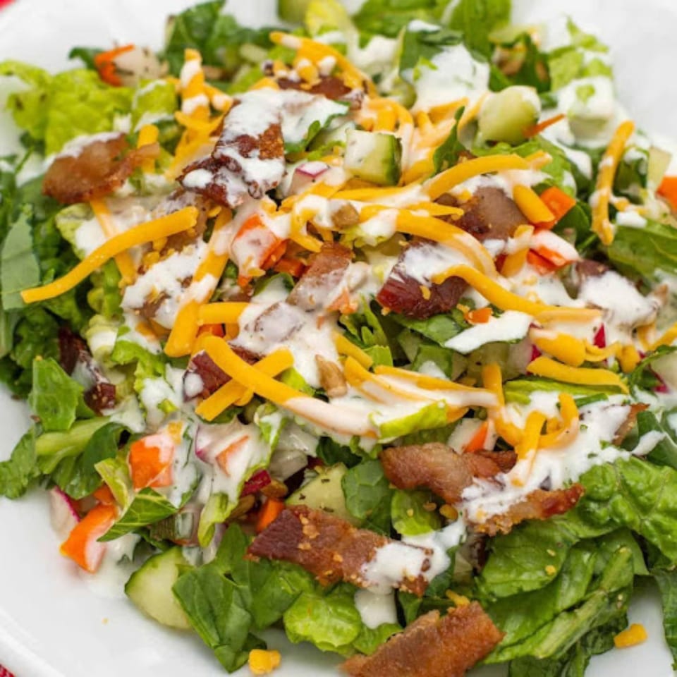 Close-up of a fresh Grille No. 13 house salad with lettuce, bacon, shredded cheese, and ranch dressing.