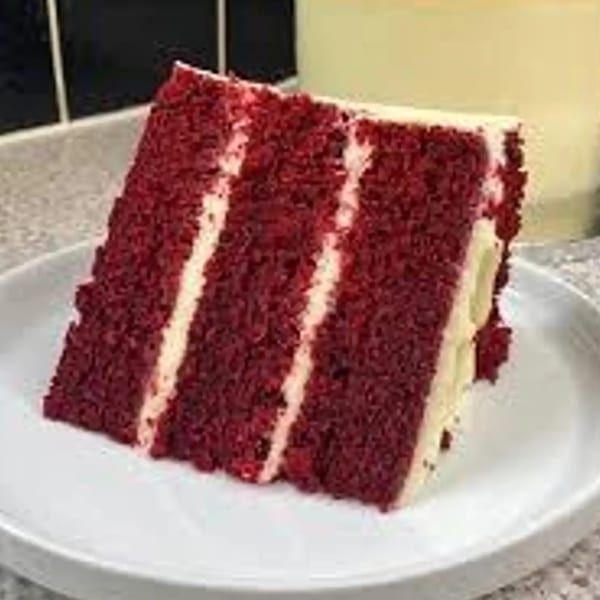 A slice of Grille No. 13's red velvet cake with white frosting layers on a white plate.