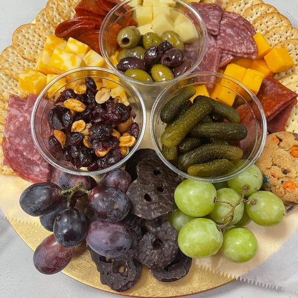 A Grille No. 13 charcuterie board with meats, cheeses, crackers, grapes, pickles, olives, and nuts.