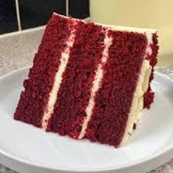 A slice of Grille No. 13's red velvet cake with white cream cheese frosting layers on a white plate.