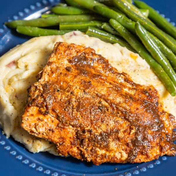Grille No. 13's blackened chicken with mashed potatoes and green beans on a blue plate.