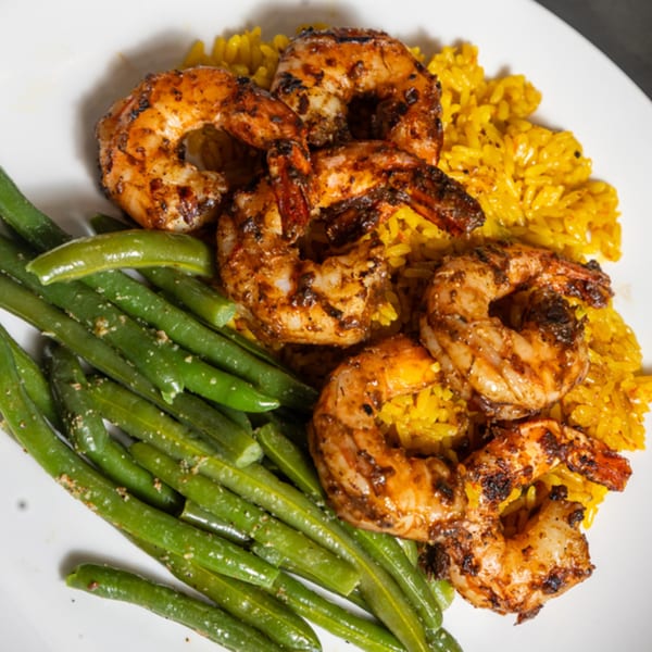 Grilled shrimp with yellow rice and green beans on a white plate at Grille No. 13.