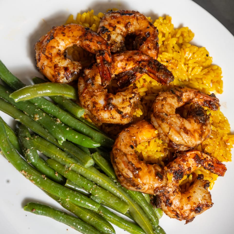 Grilled shrimp with yellow rice and green beans on a white plate at Grille No. 13.