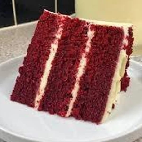 A slice of Grille No. 13's red velvet cake with white cream cheese frosting layers on a white plate.